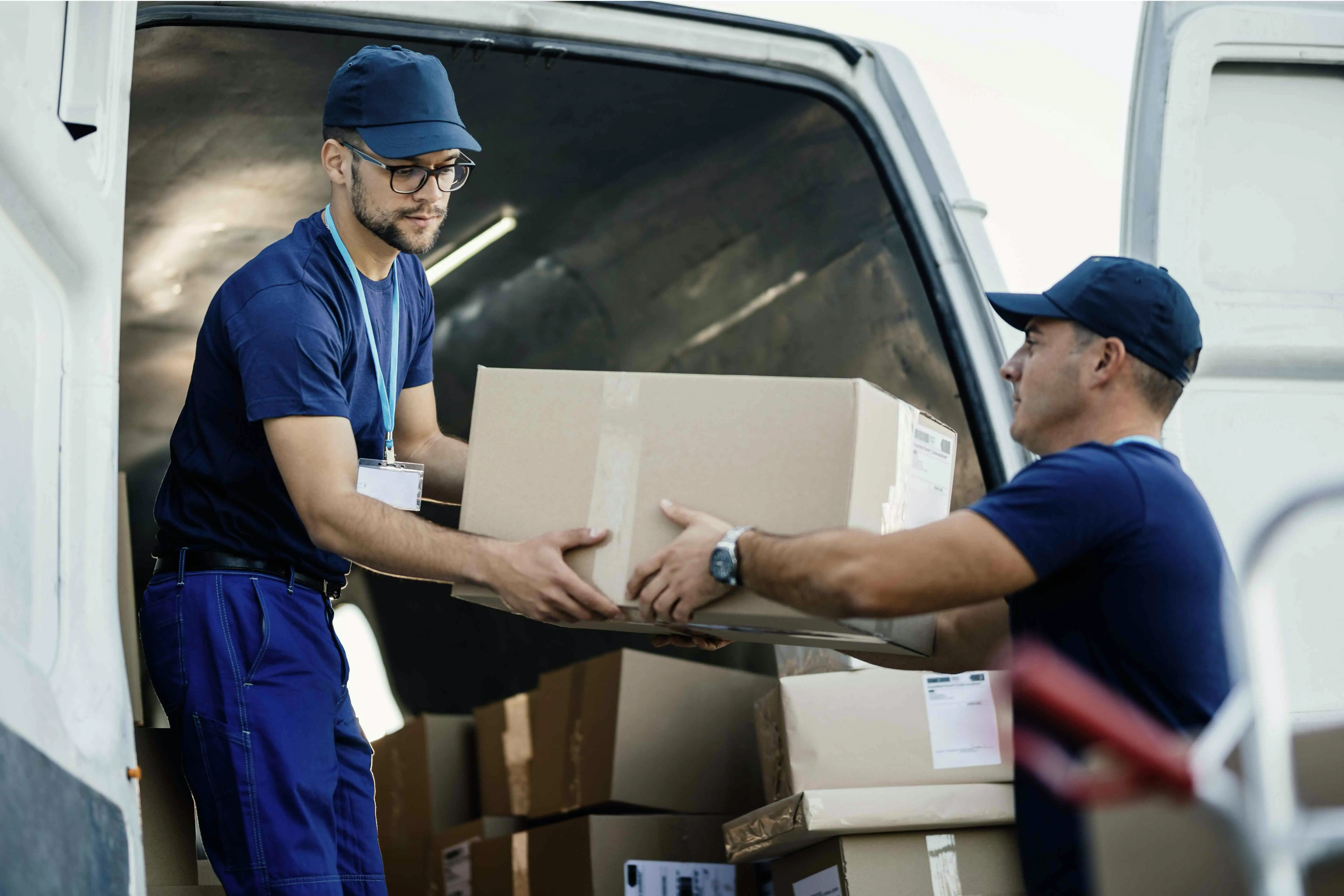delivery men-loading-carboard-boxes-van-while-getting-ready-shipment