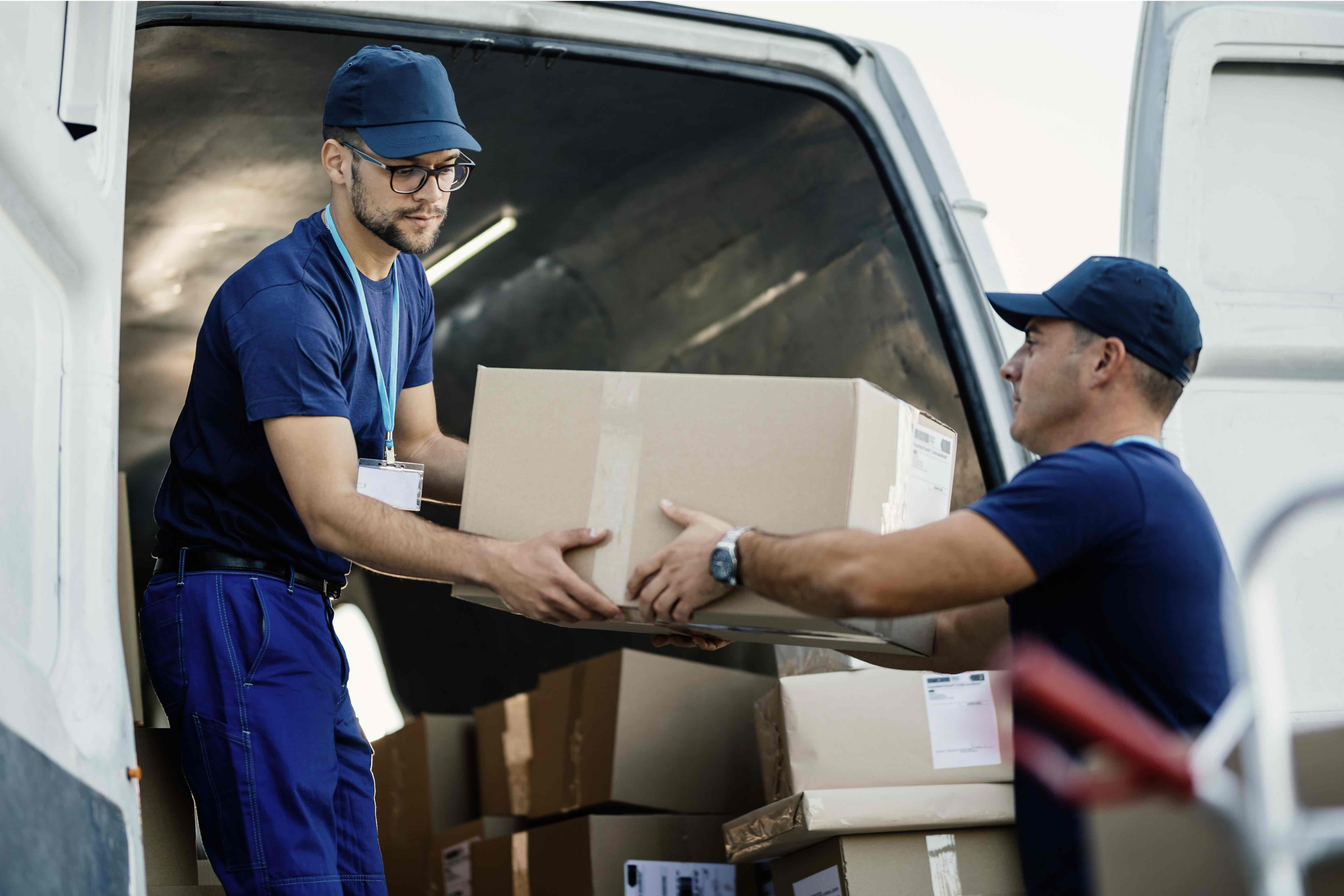 delivery men-loading-carboard-boxes-van-while-getting-ready-shipment